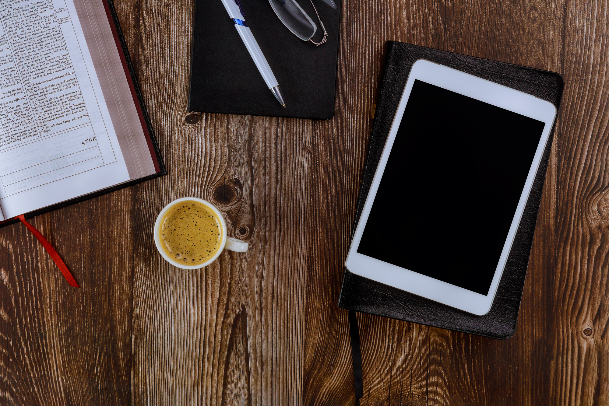 Cup of Coffee, Bible, Tablet, Pen and Eyeglasses on Table